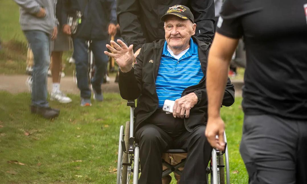 WWII veteran is accompanied by VFW members as he returns to Europe where he served and was held as a POW during the war