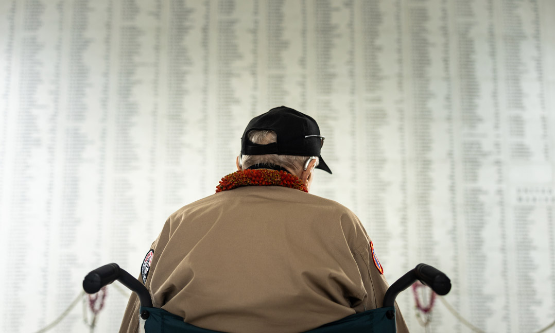 Pearl Harbor survivor sits in wheelchair in front of the memorial