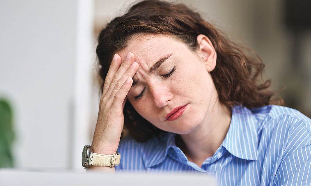 woman holding forehead indicating headache