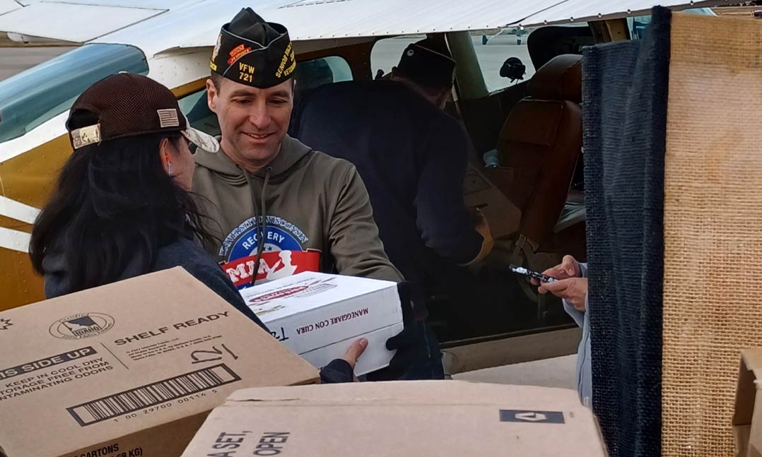 VFW Senior Vice Commander-in-Chief Cory Geisler helps load donated food onto an aircraft